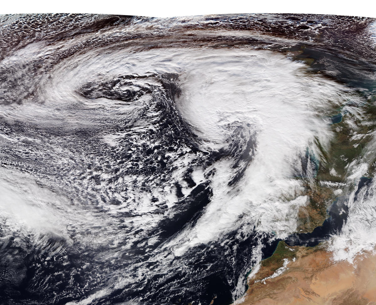 Overhead view of a storm, with clouds swirling in the foreground, and water and land in the background.