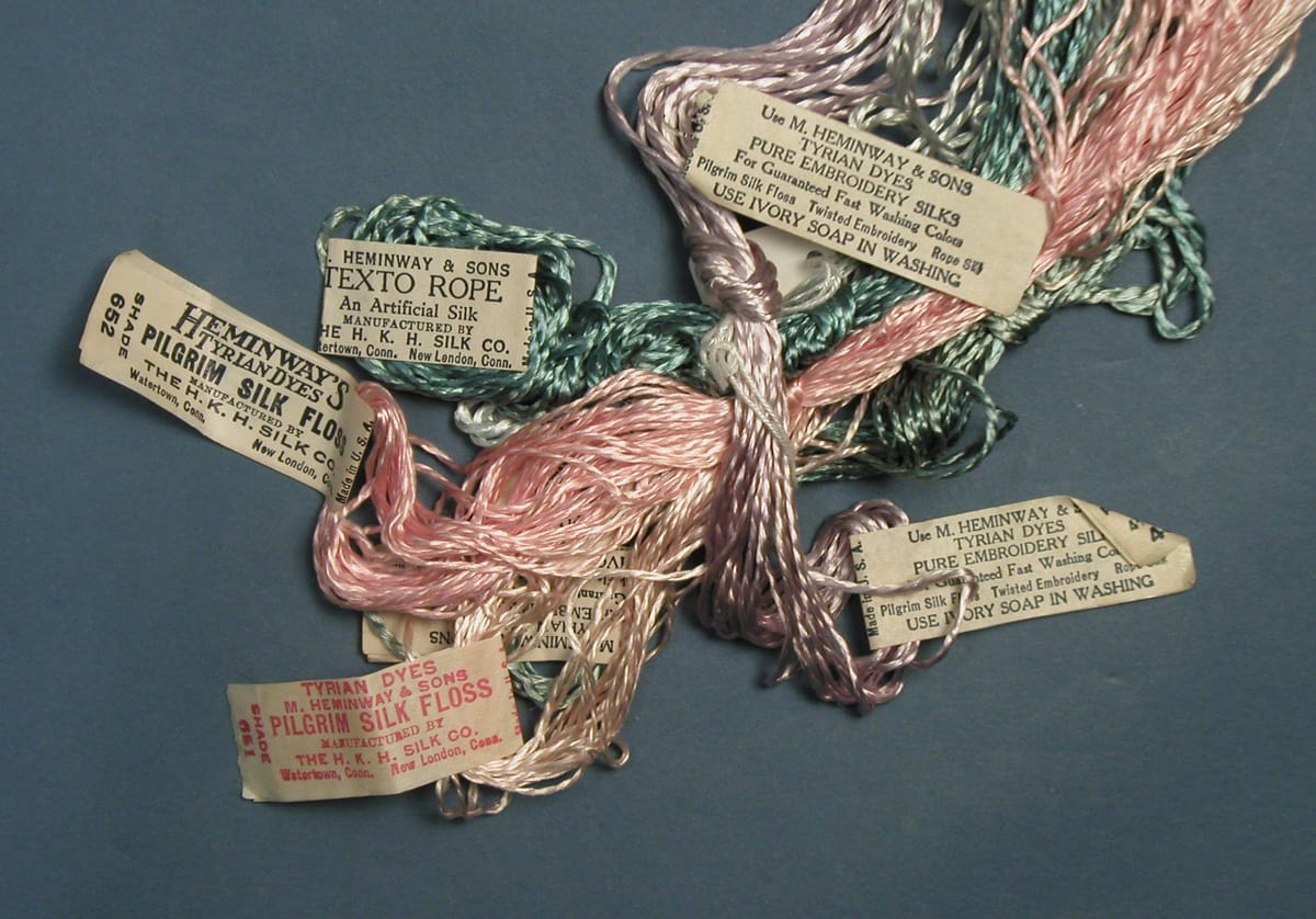 A photo of several bundles of embroidery floss in pastel colours, all tangled together. The bundles still have their tags.