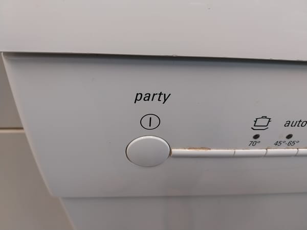 Close-up of the front panel of a dishwasher. Over the power button, there is a label which says "party."