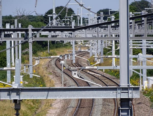 A photo of a curving, double-railway line, with a large metal gantry made of I-beams in the foreground.
